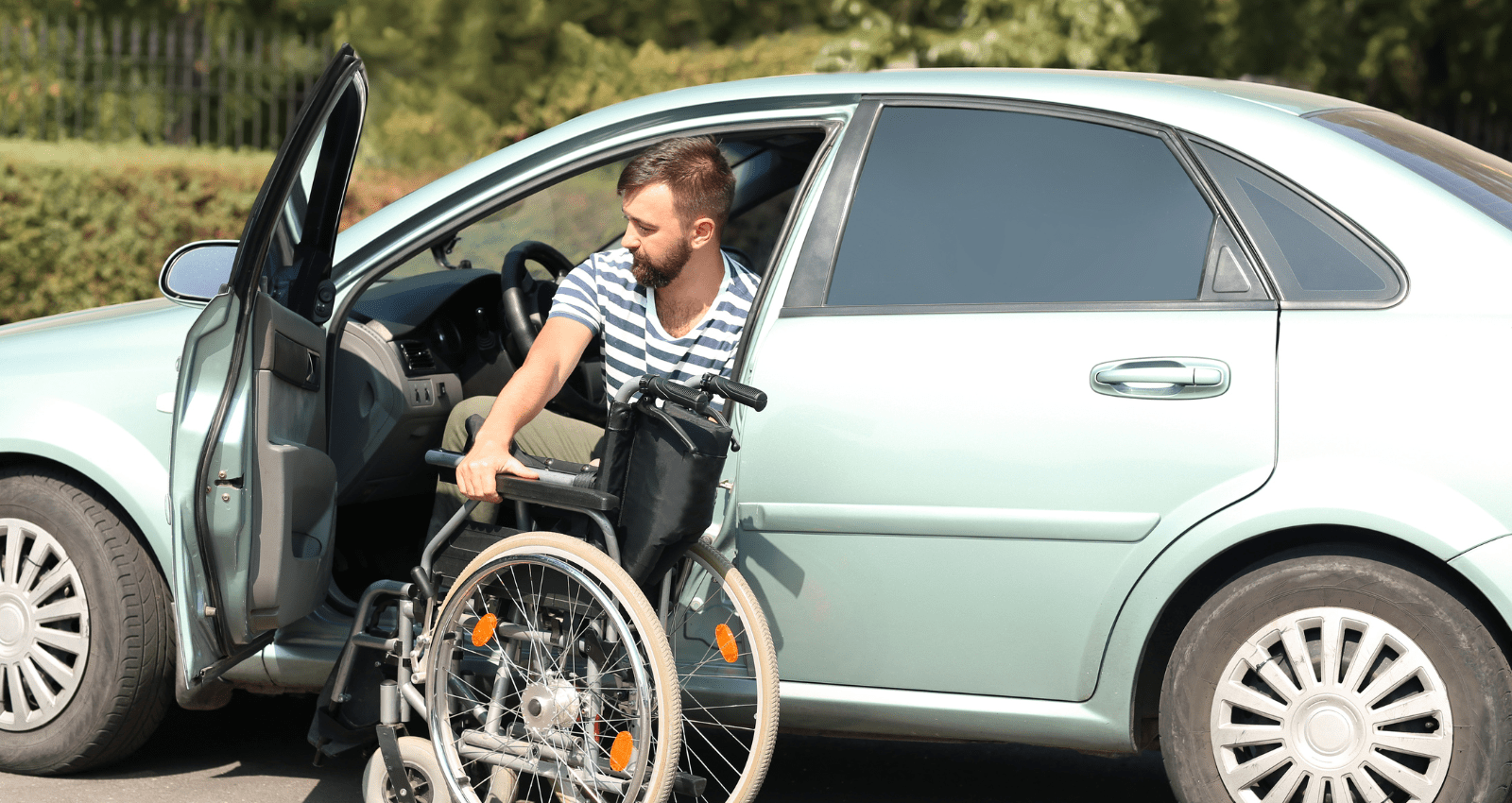 homme barbu qui descend de sa voiture et qui va déplier son fauteuil roulant