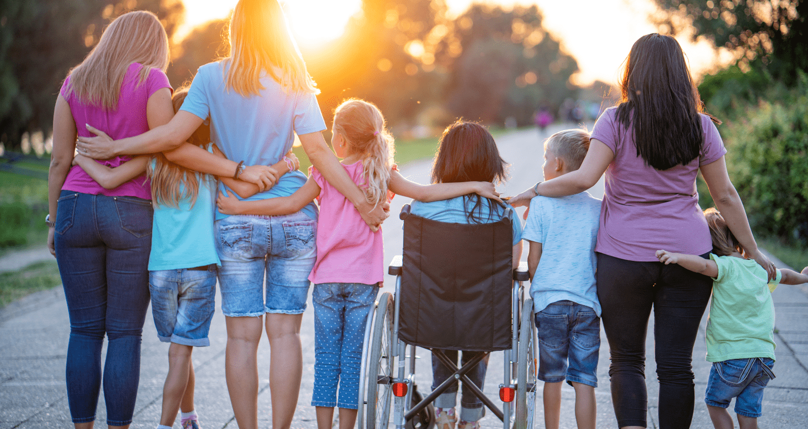 groupe d'enfants de dos côte à côte et qui s'enlace sur un décor en extérieur avec un couché de soleil en face. l'un des enfants et une fille brune en fauteuil roulant